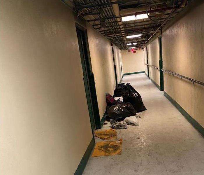 School hallway covered in a thin layer of soot with fire related trash outside a door.